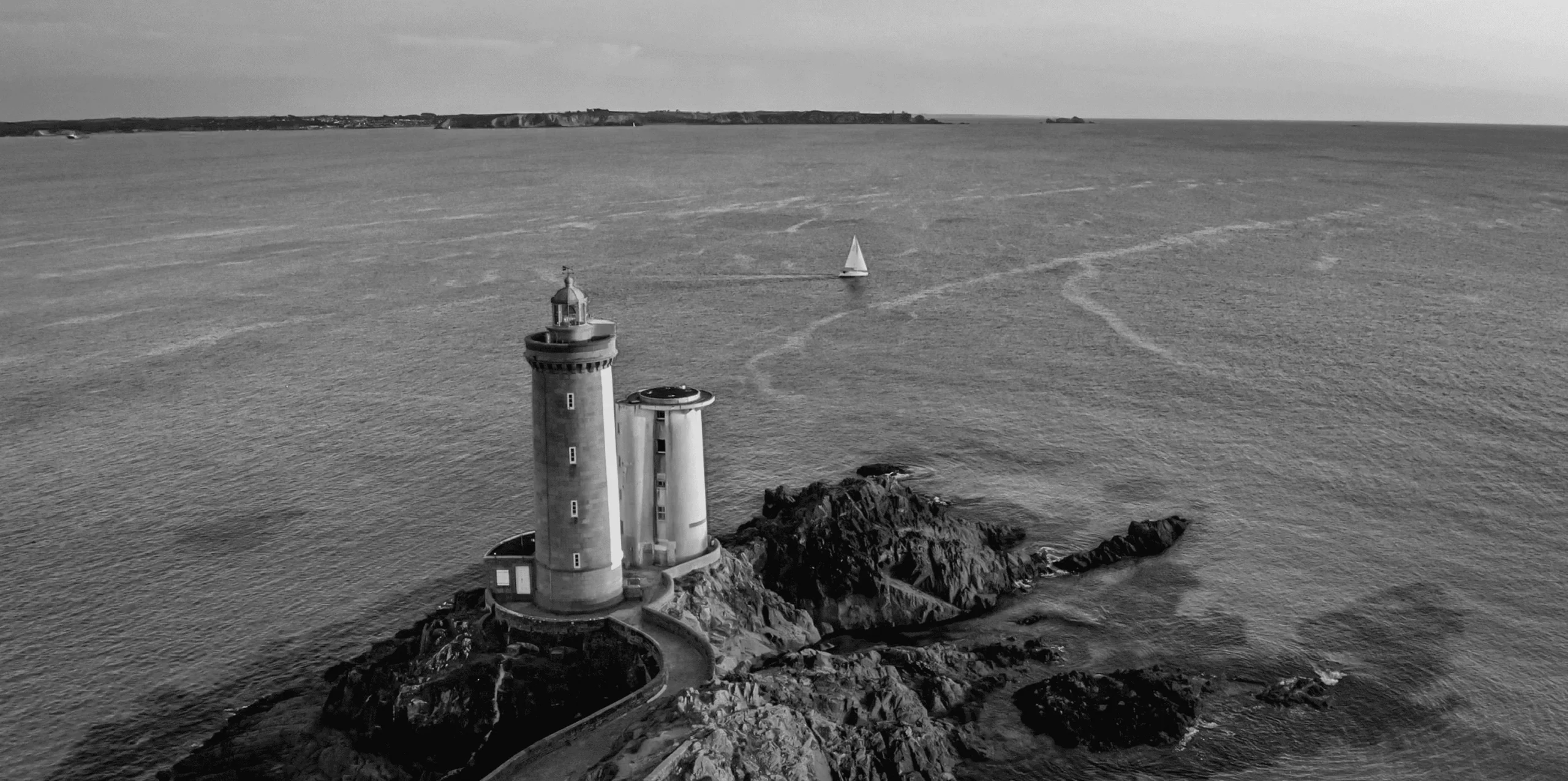 Vue aérienne d'un magnifique paysage marin avec un phare blanc et un voilier en arrière-plan